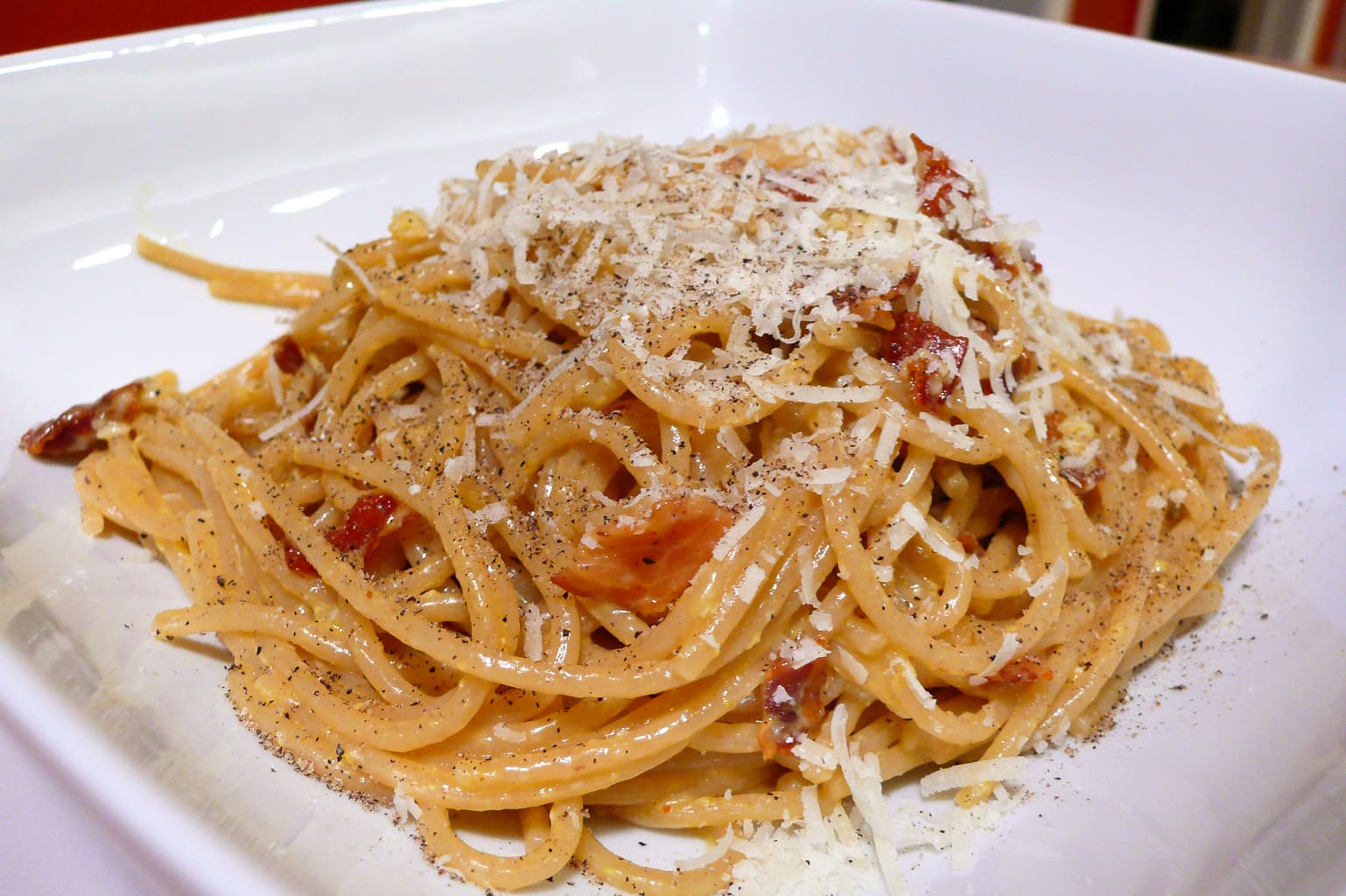 Spaghetti carbonara twirled in a bowl with pancetta and black pepper